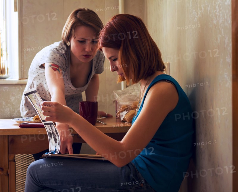 Caucasian women reading magazine at table