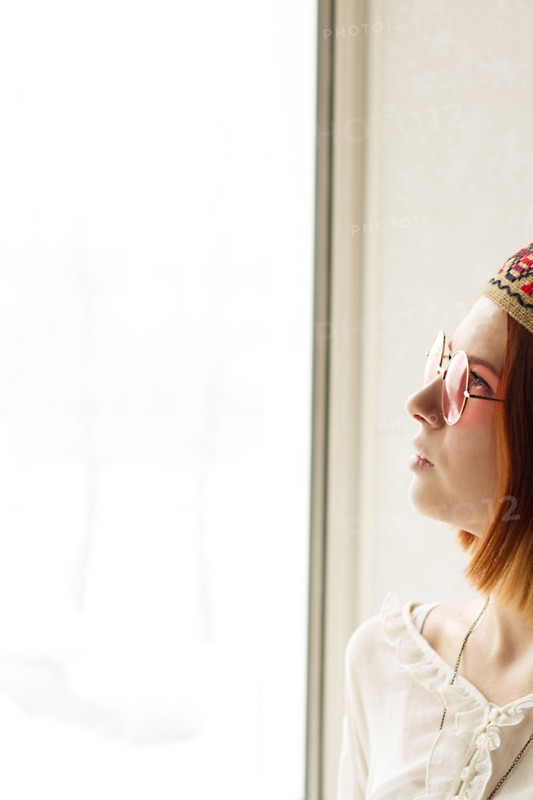 Caucasian woman wearing sunglasses near window