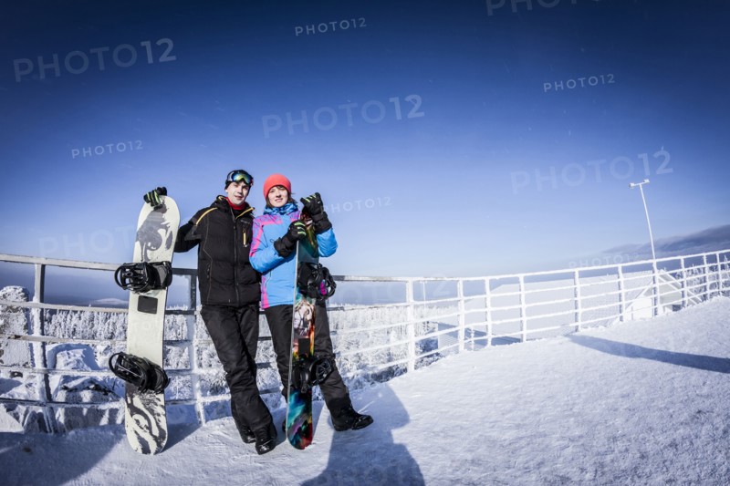 Caucasian snowboarders standing on mountaintop