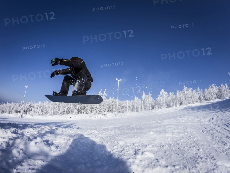 Caucasian snowboarder jumping on snowy slope