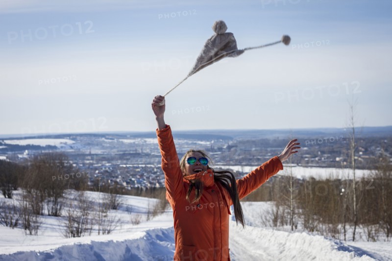 Caucasian woman swinging hat in snowy rural landscape