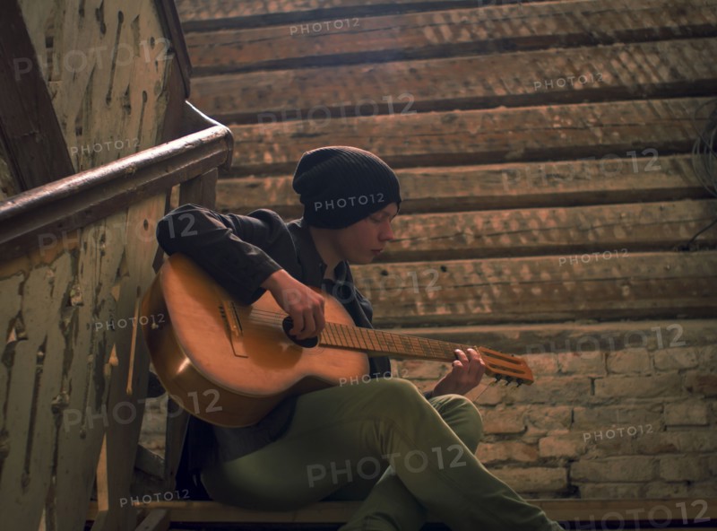 Caucasian man playing guitar on staircase