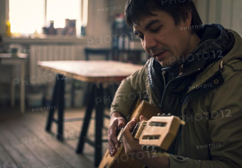 Asian man playing guitar in living room