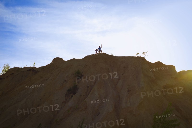 People standing on hilltop under blue sky