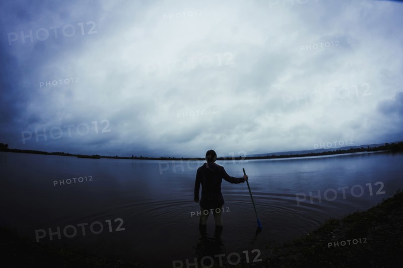 Caucasian man standing in still remote lake