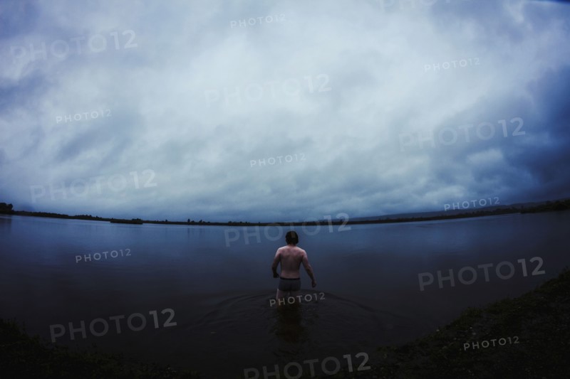 Caucasian man standing in still remote lake