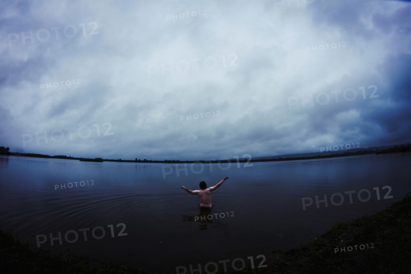 Caucasian man standing in still remote lake