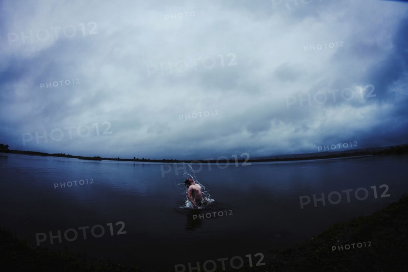 Caucasian man splashing in still remote lake