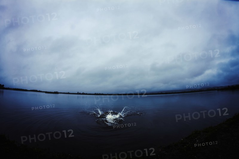 Caucasian man splashing in still remote lake