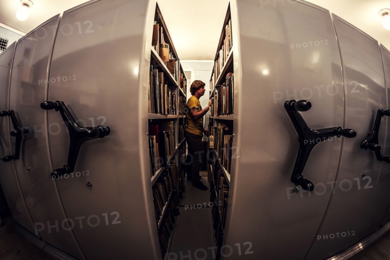 Caucasian man searching old newspapers in library archive