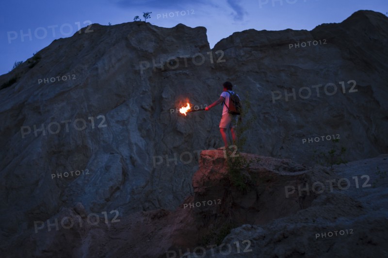 Caucasian man holding torch under rocky cliff