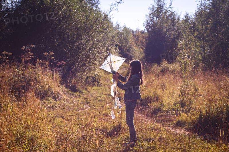 Caucasian teenage girl holding kite in field
