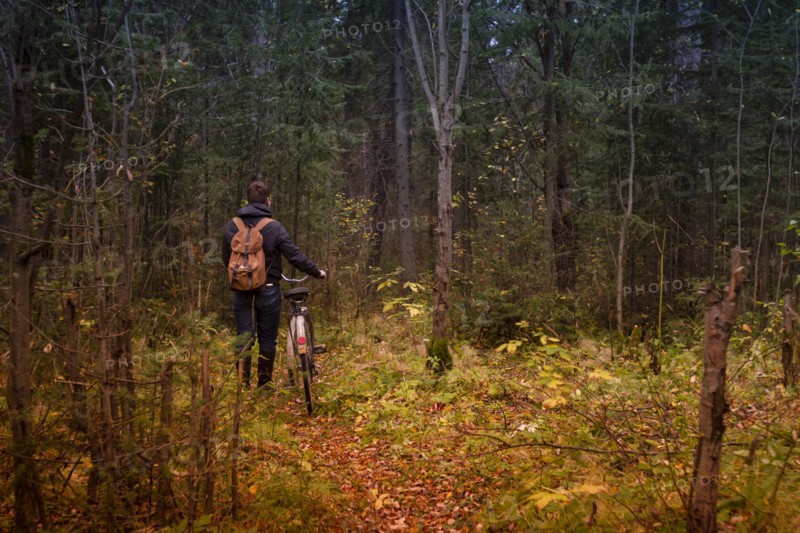 Caucasian man pushing bicycle on forest path