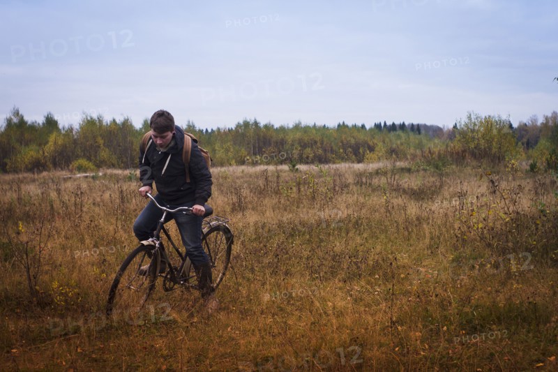 Caucasian man riding bicycle in field
