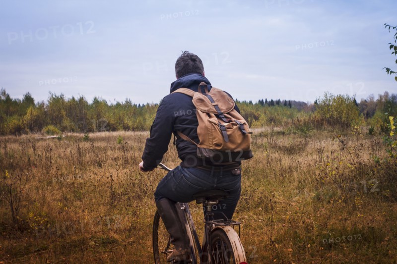 Caucasian man riding bicycle in field