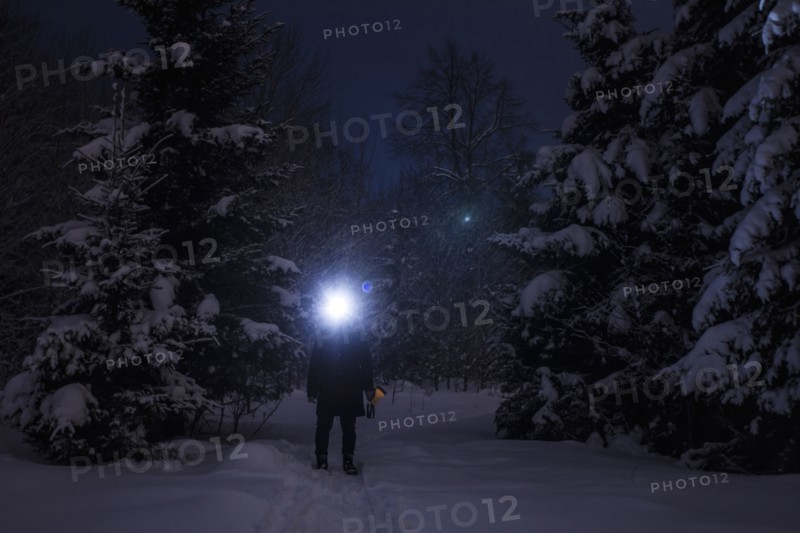 Caucasian hiker wearing headlamp in snowy forest