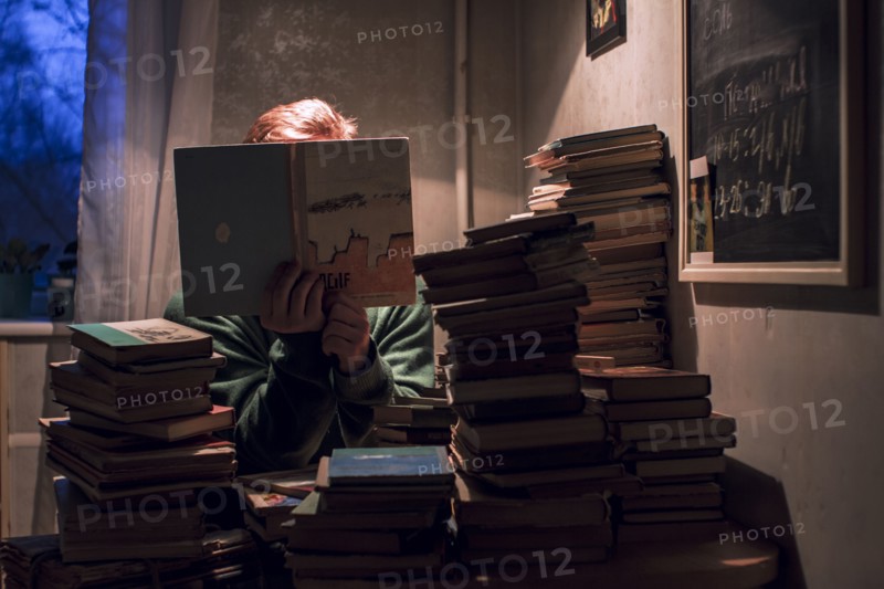Caucasian man reading stack of books