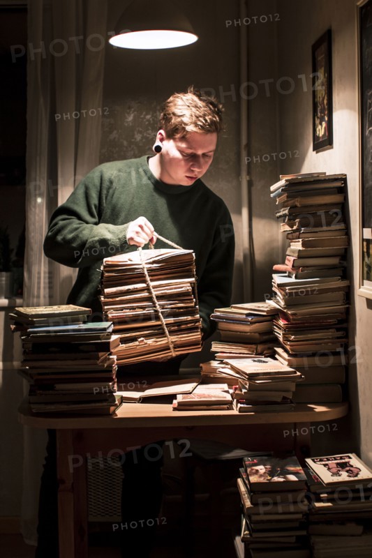 Caucasian man holding stack of books