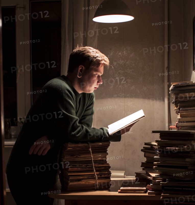 Caucasian man reading stack of books