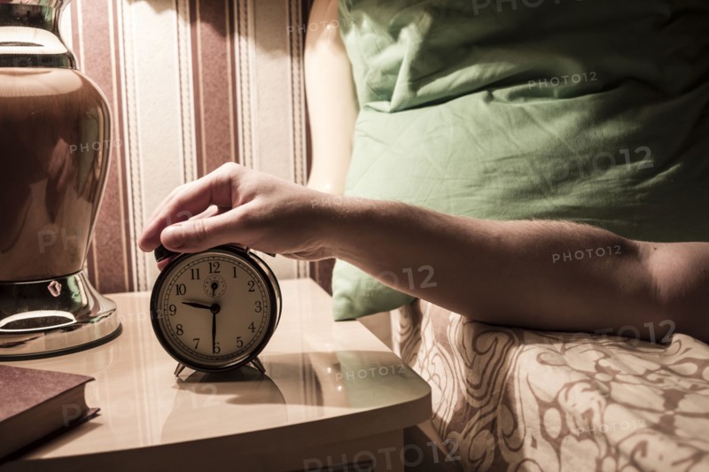 Caucasian man turning off alarm clock
