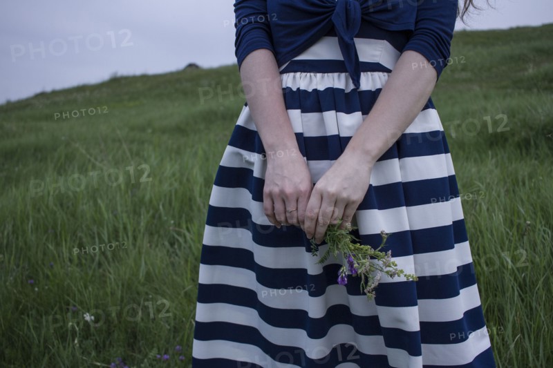 Caucasian woman holding wildflowers in field of grass