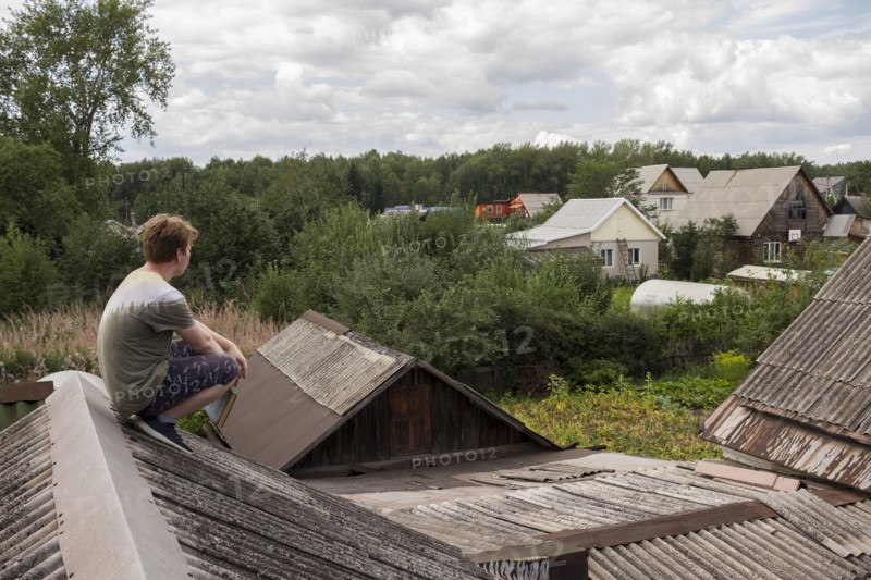 Caucasian man sitting on roof holding book
