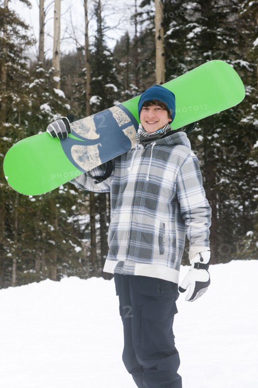 Mixed race snowboarder carrying snowboard