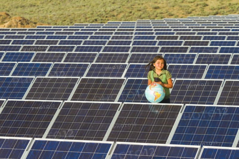 Native American girl standing near solar panels holding globe