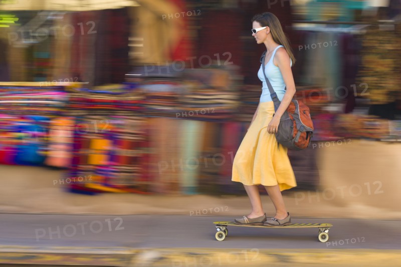 Caucasian woman skateboarding on sidewalk