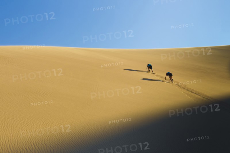 Hispanic couple climbing sand dune