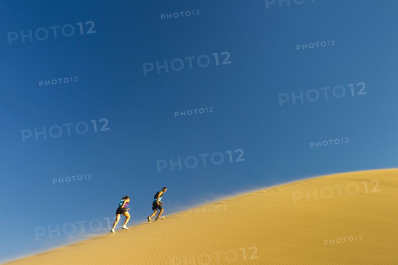 Hispanic couple climbing sand dune