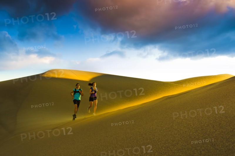 Hispanic couple running on sand dune