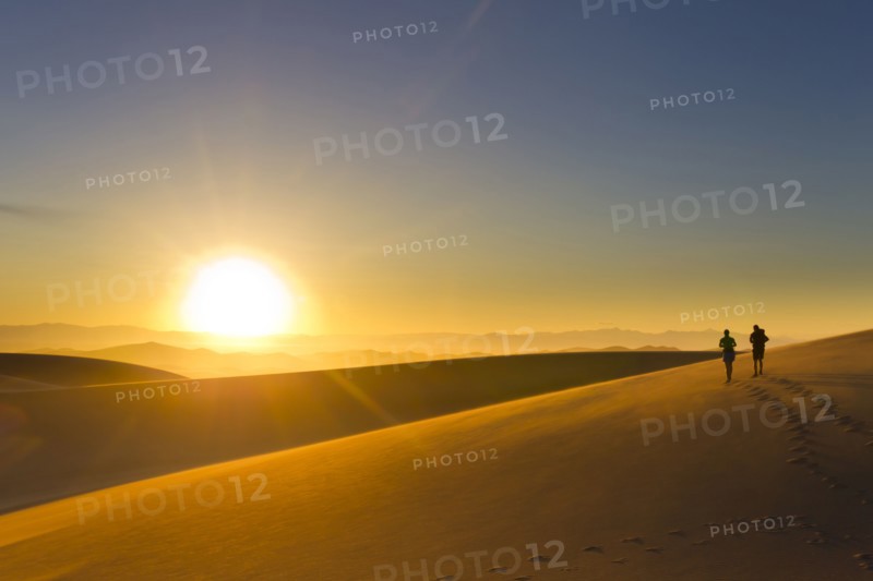 Hispanic couple walking on sand dune at sunset