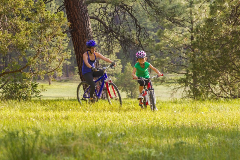 Mother and daughter riding mountain bikes in meadow