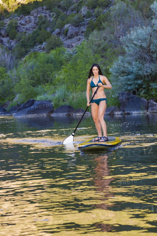 Hispanic woman riding paddle board