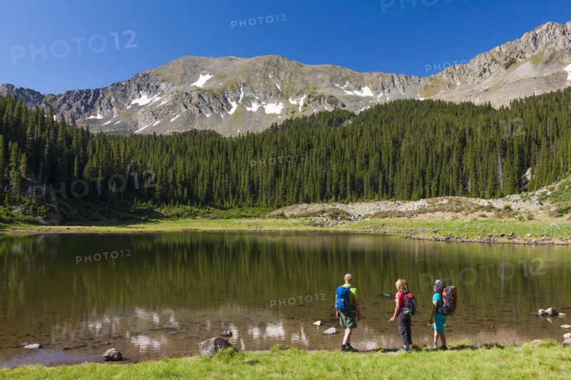 Hikers admiring still lake in rural landscape