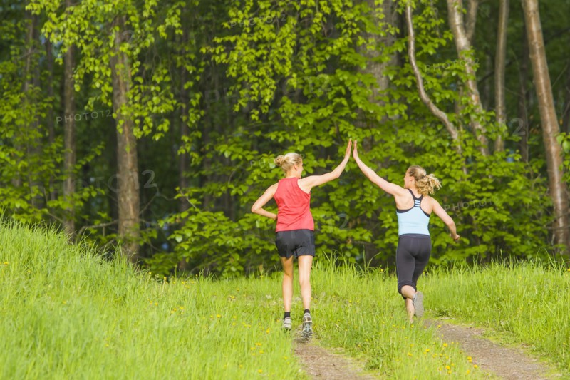 Caucasian runners high fiving on path