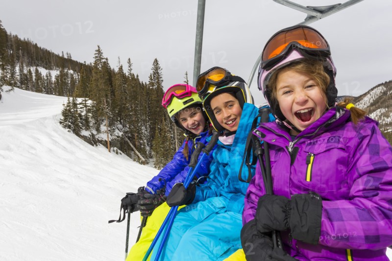 Girls riding ski lift on snowy slope