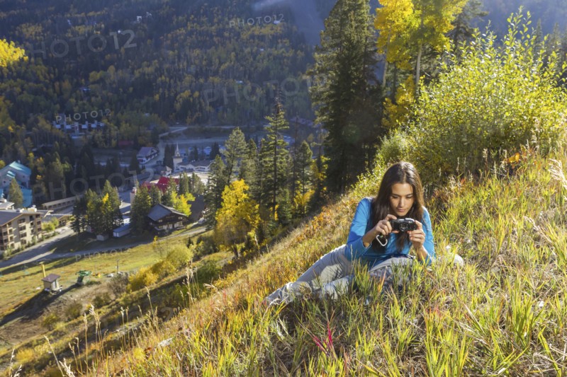 Mixed race woman taking pictures on rural hillside