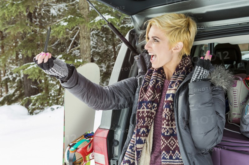 Caucasian woman at car posing for cell phone selfie in winter