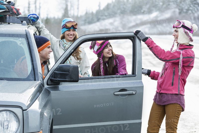 Friends laughing near car in winter