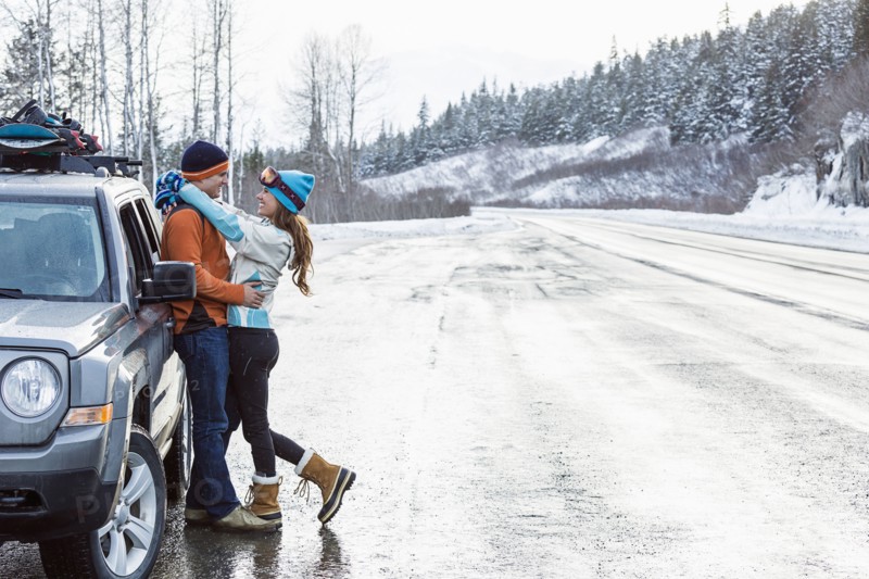 Caucasian couple hugging near car in winter