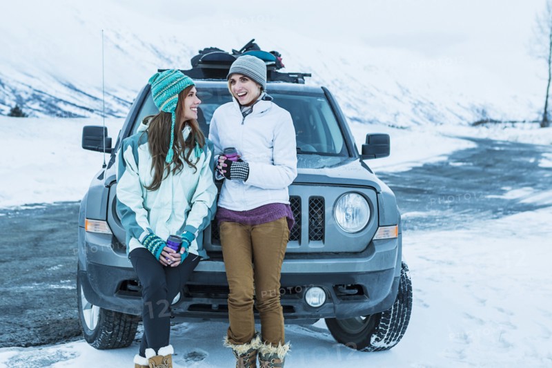 Caucasian women laughing near car in winter