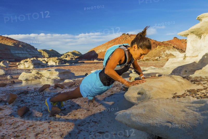 Native American woman doing push-up on rock in desert