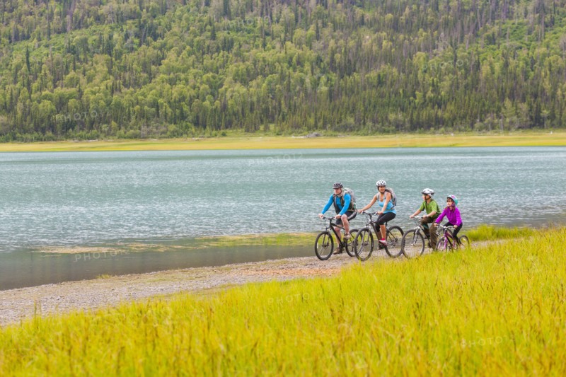 Couple with son and daughter riding bicycles near lake