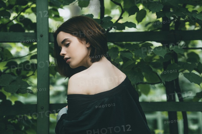 Caucasian woman baring shoulder near foliage
