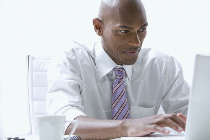 Mixed race businessman using laptop at desk