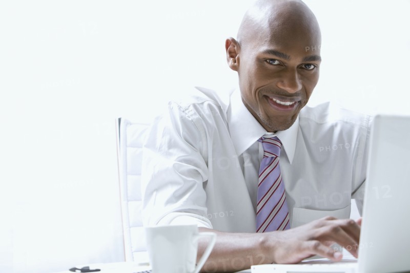 Mixed race businessman using laptop at desk