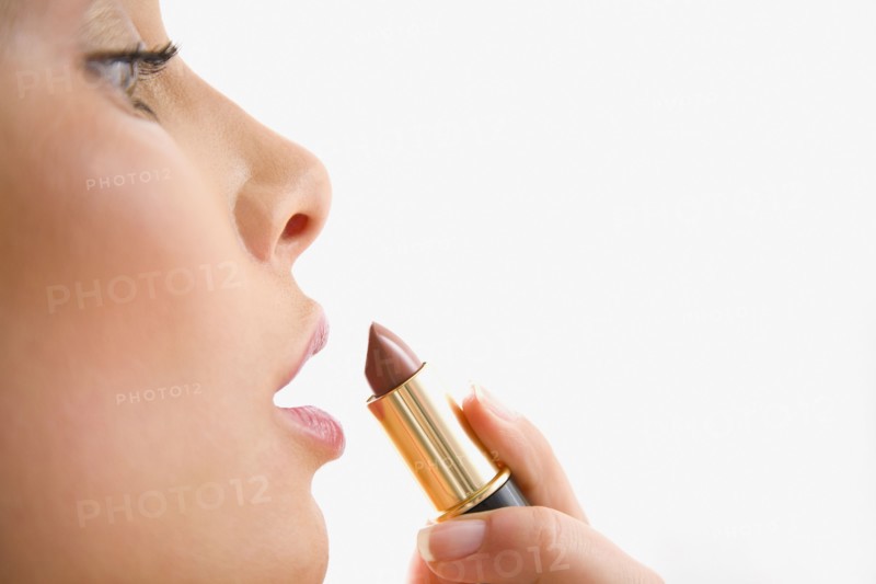 Mixed race woman applying lipstick