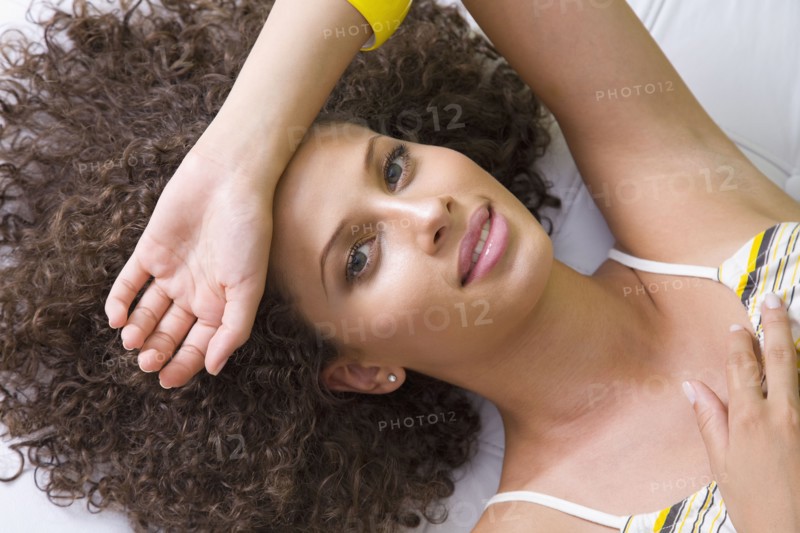 Mixed race woman laying with arm over forehead